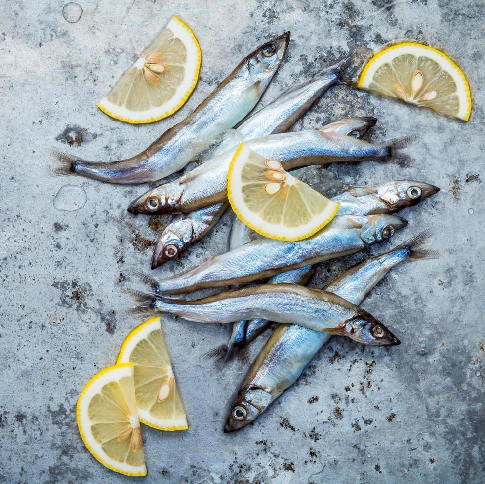 Shishamo fish and lemon on a shabby metal background photo