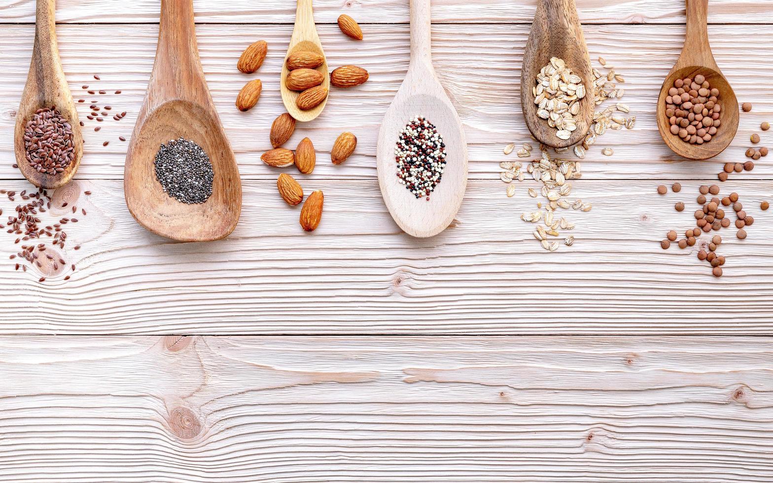 Granos y nueces en cucharas sobre un fondo de madera blanca foto