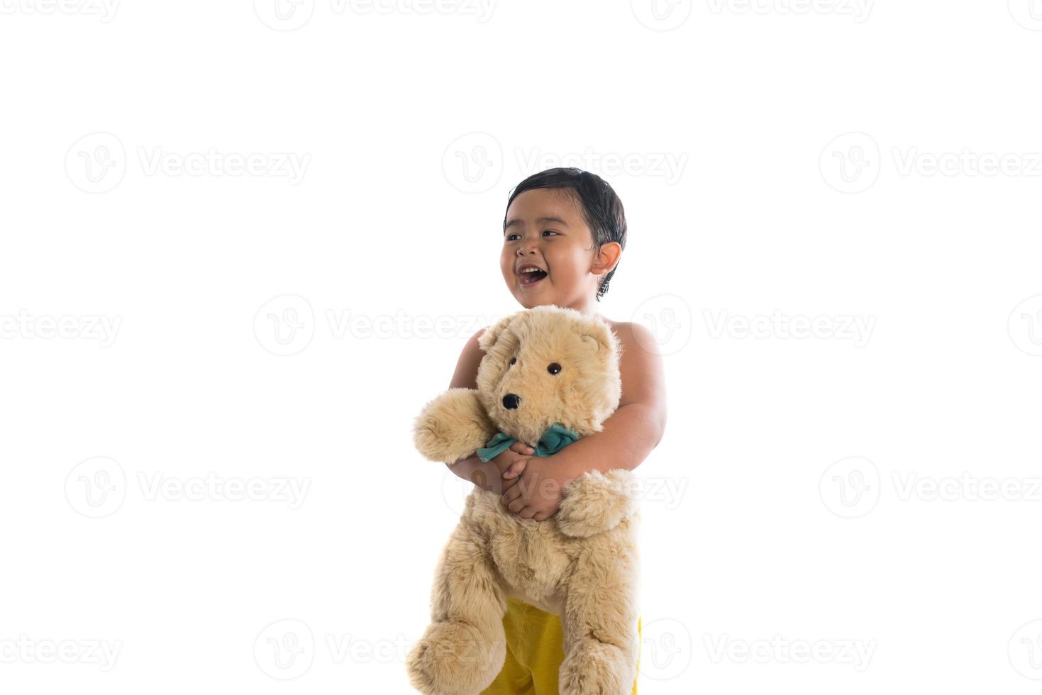 Niño asiático sosteniendo un gran oso de peluche aislado sobre fondo blanco. foto