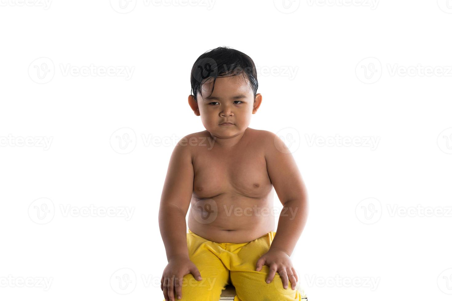 Little Asian boy with angry confused expression on face sitting isolated on white background photo
