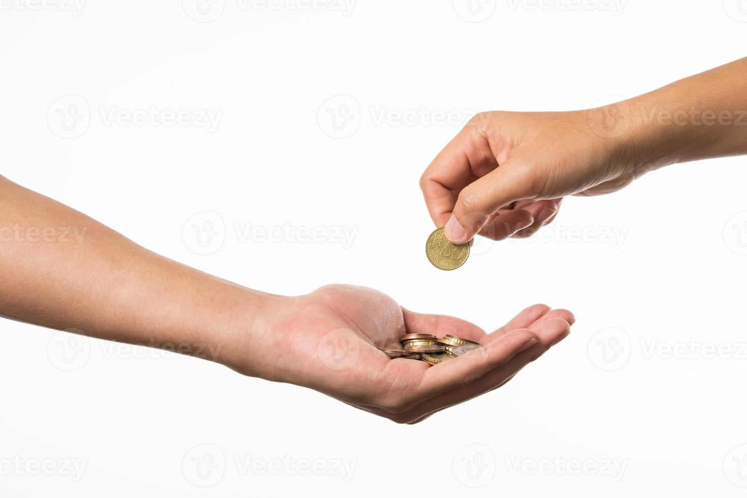 Hand giving golden coins to another hand photo