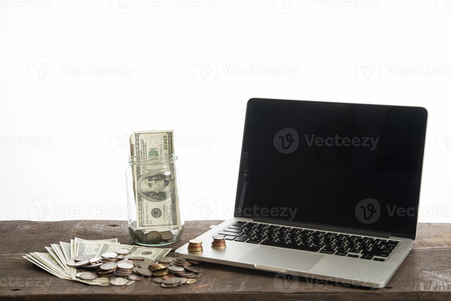 Laptop with coins and dollar bank isolated on white background photo