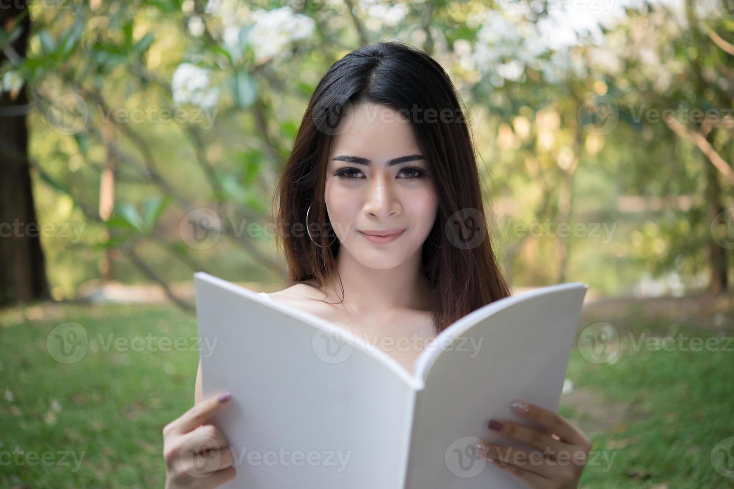 Young beautiful woman sitting and reading a book in the park photo