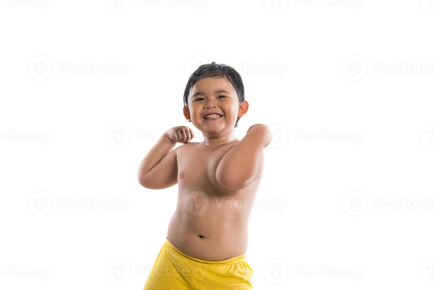 Niño gracioso mostrando músculos fuertes aislado sobre fondo blanco. foto