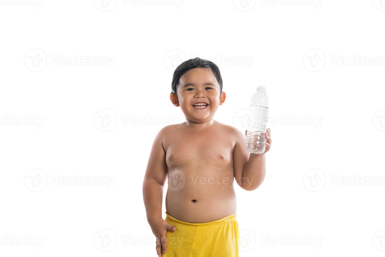 Niño feliz sosteniendo una botella de agua aislado sobre fondo blanco. foto