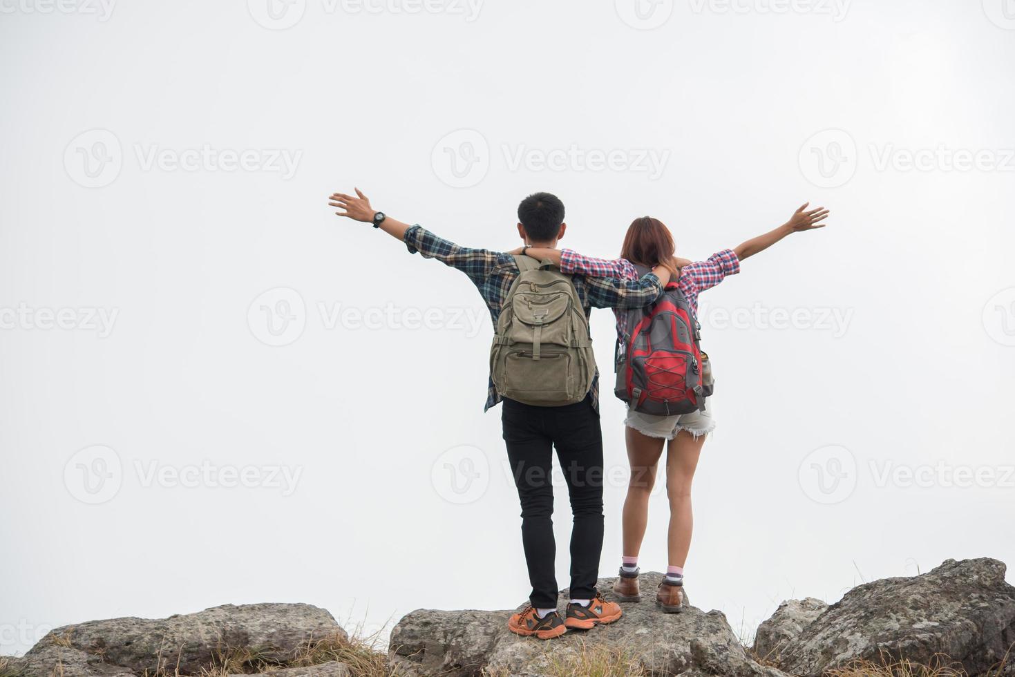 excursionistas con mochilas de pie en la cima de una montaña y disfrutando de la vista de la naturaleza foto