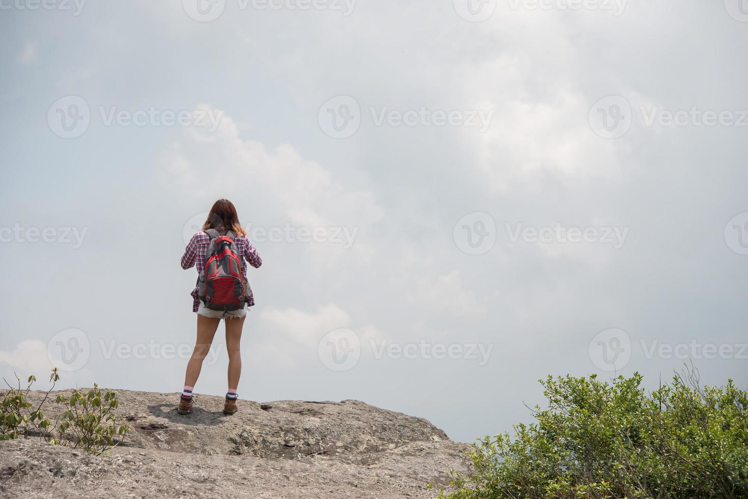 Hiker with backpack standing on top of a mountain and enjoying nature view photo