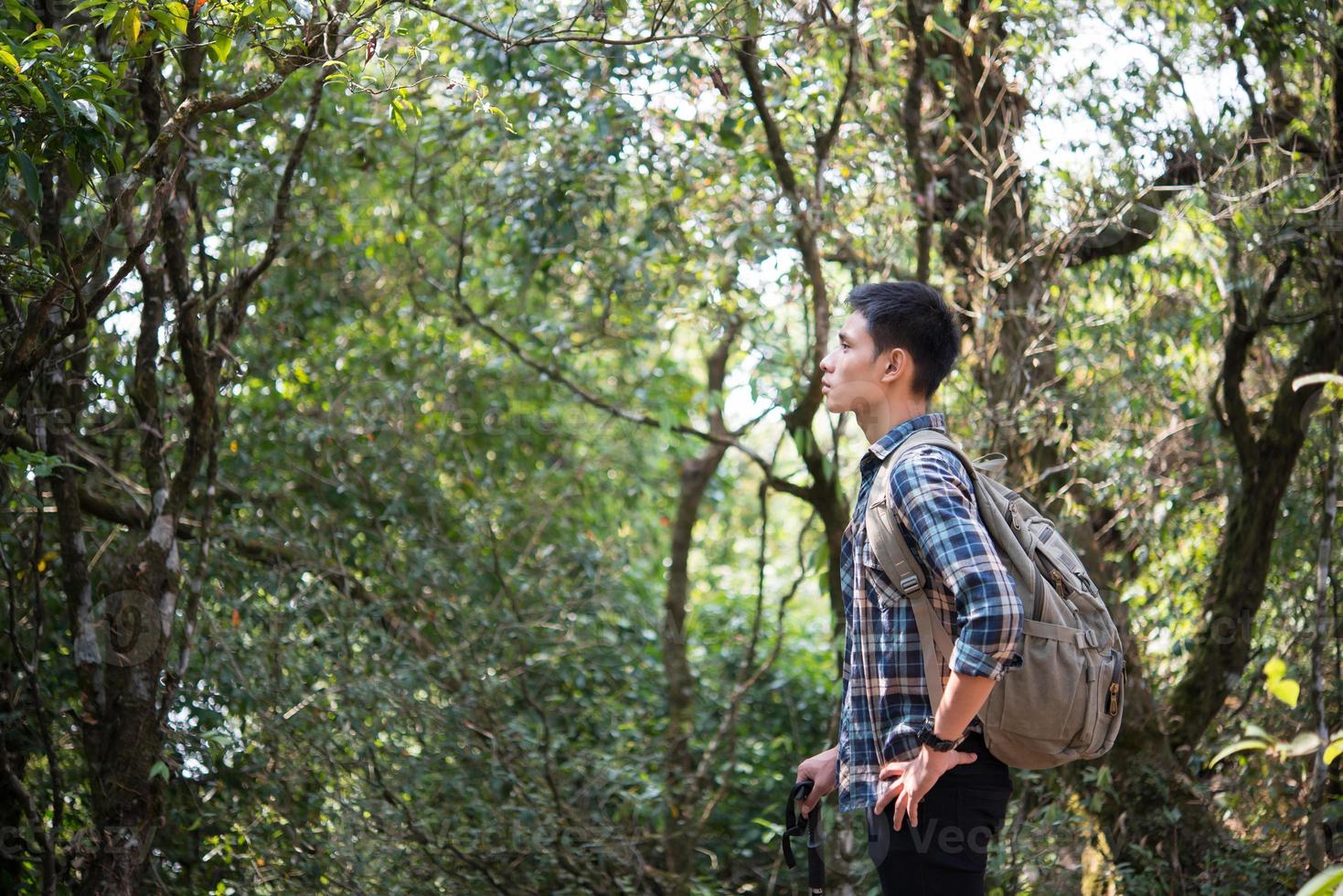 Joven excursionista hombre inconformista tomando un descanso mientras camina foto