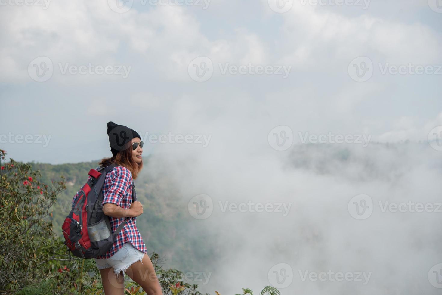 Caminante con mochila de pie en la cima de una montaña y disfrutando de la vista de la naturaleza foto
