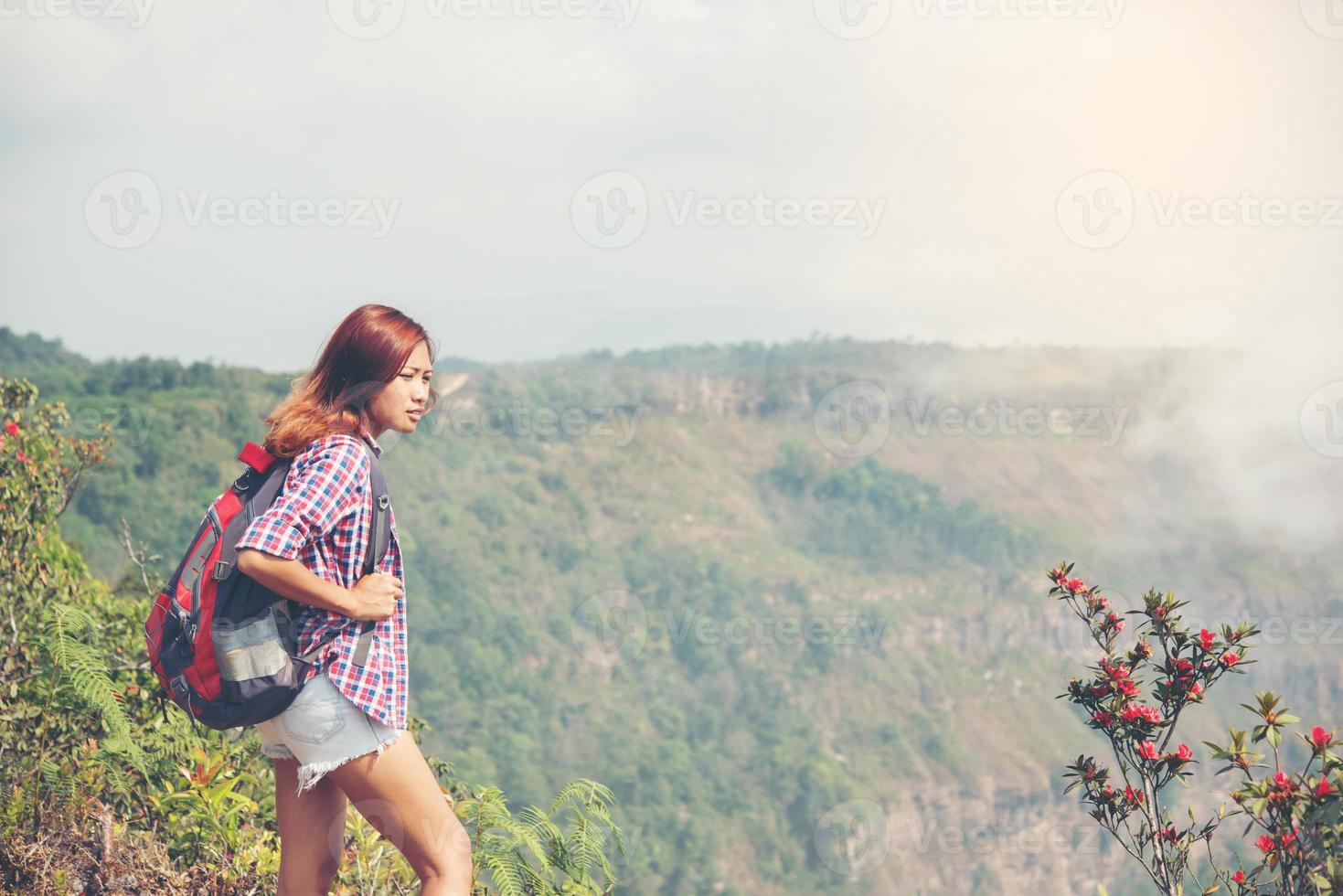 Hiker with backpack standing on top of a mountain and enjoying nature view photo