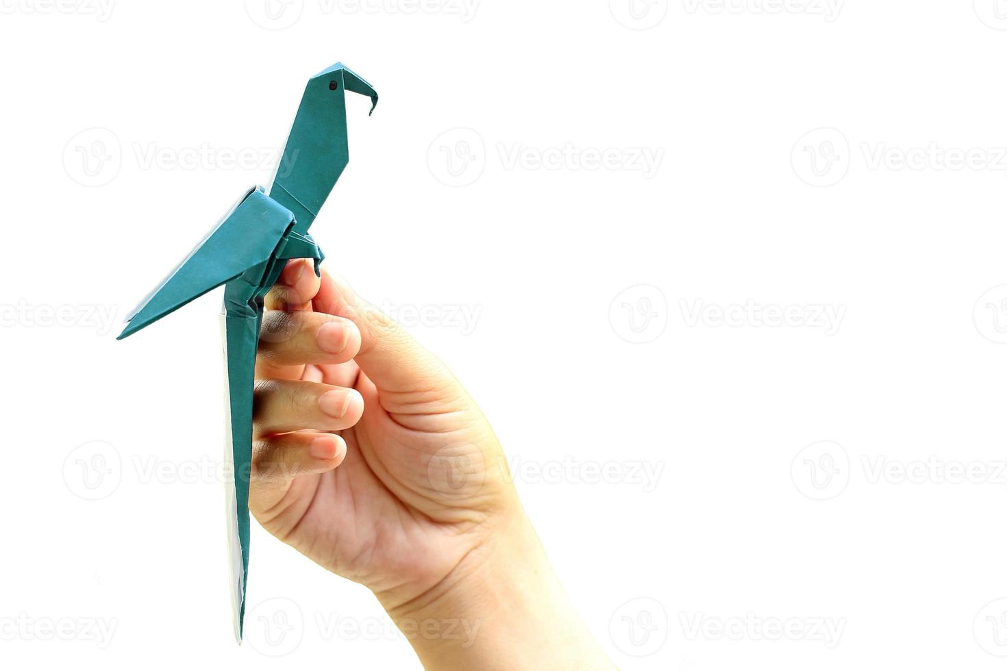 Mano de mujer sosteniendo pájaro de origami sobre fondo blanco. foto