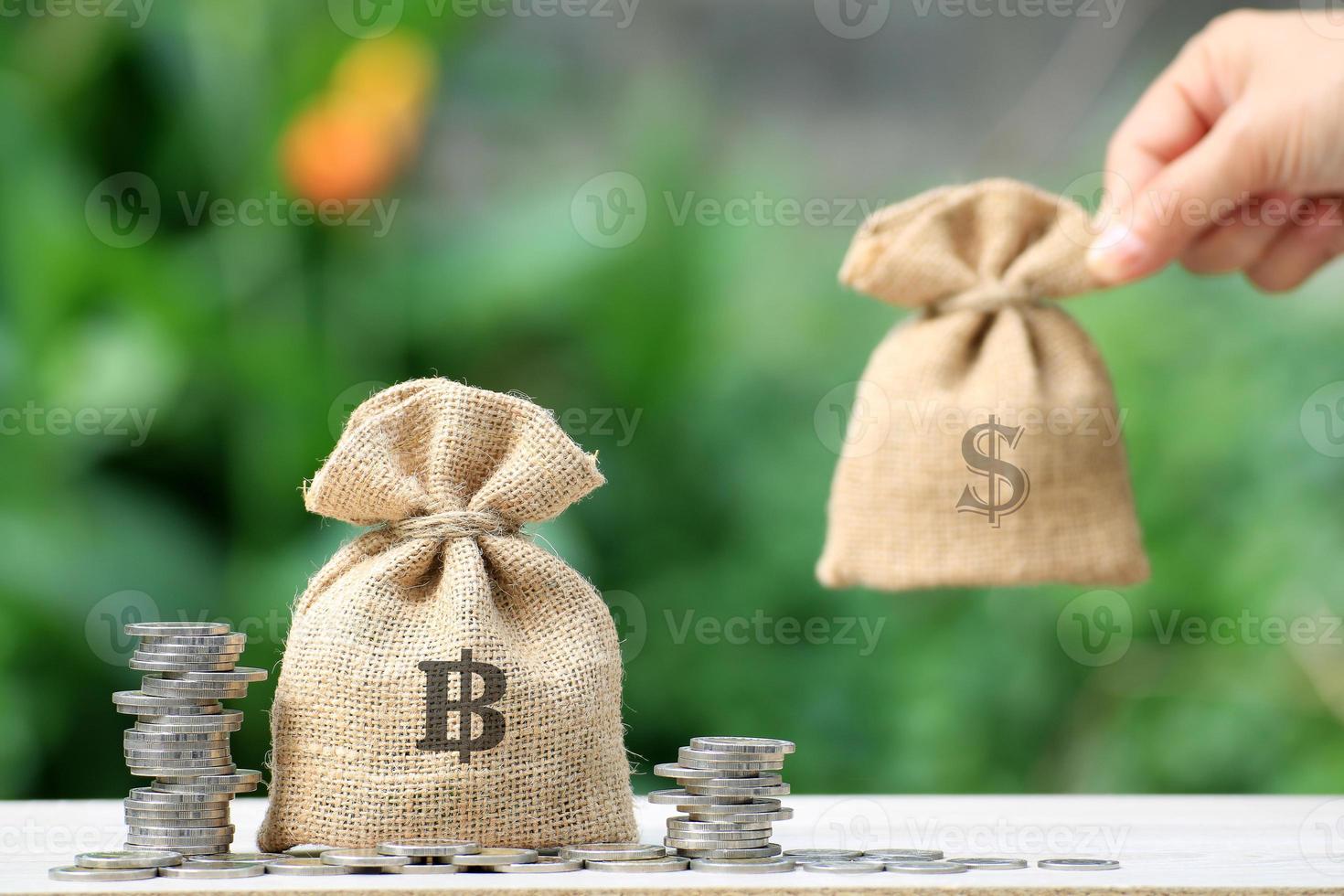 Hand with burlap money sacks next to coin stacks photo