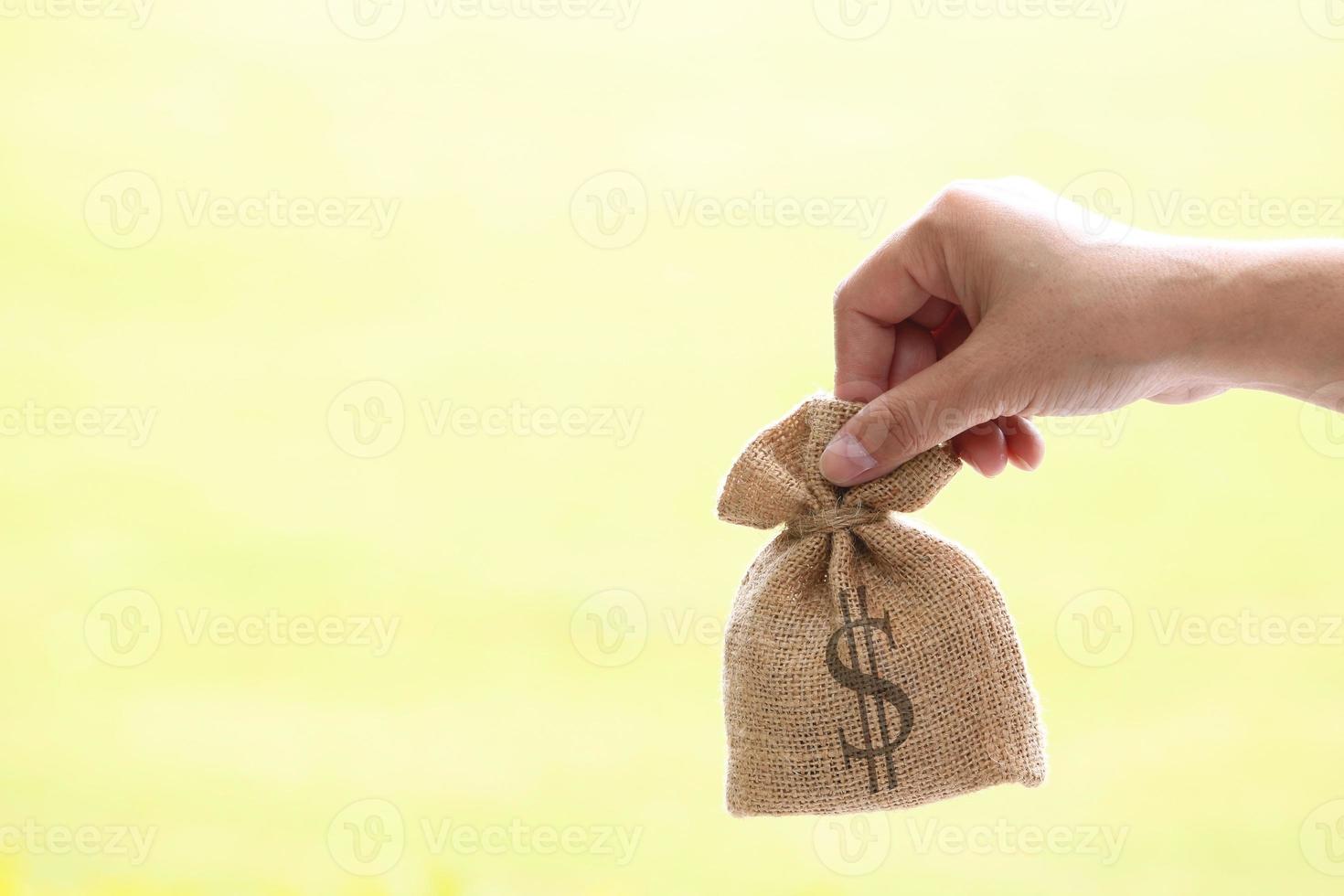 mano sujetando saco de arpillera con signo de dólar foto