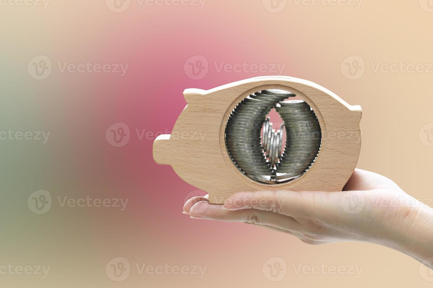 Hand holding piggy bank with coin stacks set inside photo