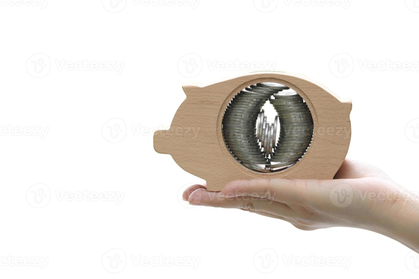 Hand holding piggy bank with coin stacks set inside on white background photo