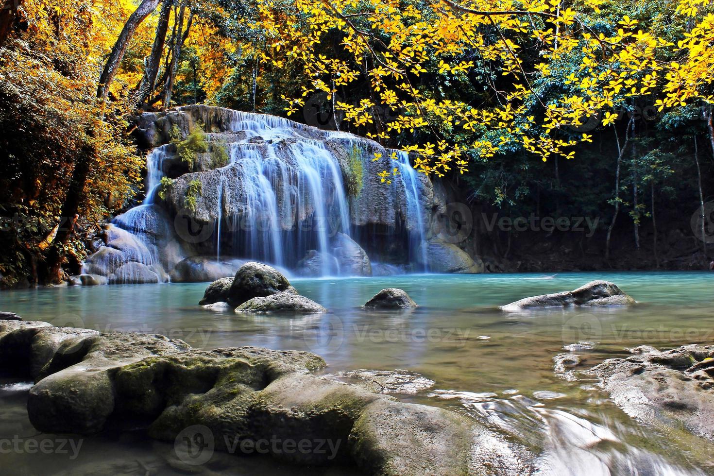 Escena de hojas amarillas y cuerpo de agua en erawan falls en Tailandia foto