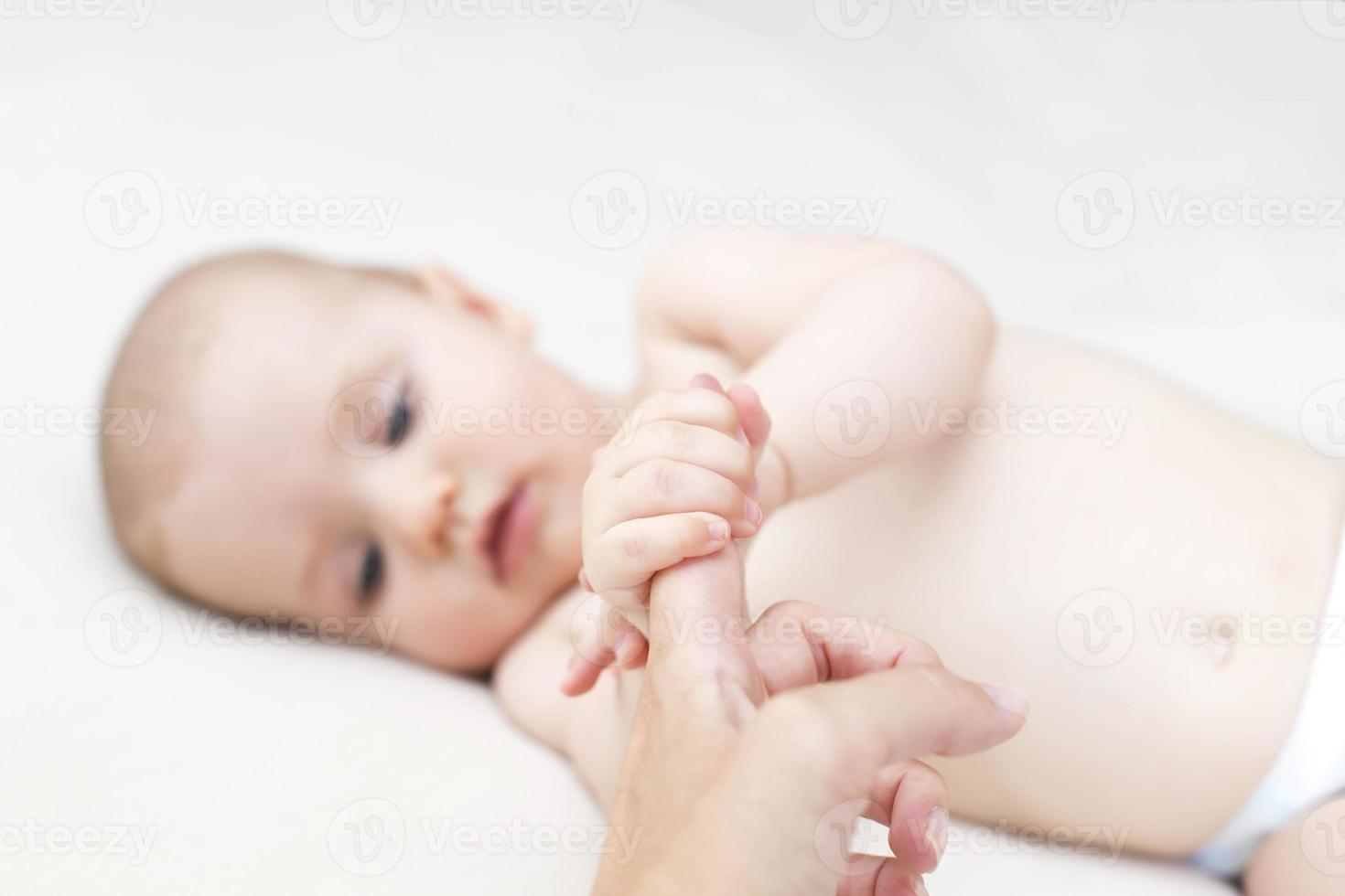 Baby girl holding mothers finger photo
