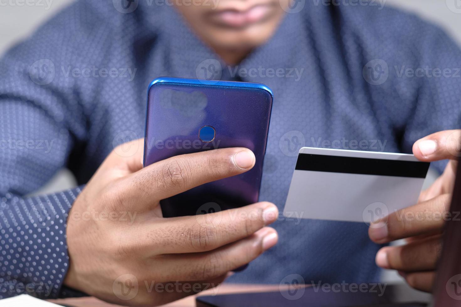 Hombre sosteniendo una tarjeta de crédito y usando un teléfono inteligente para comprar en línea foto