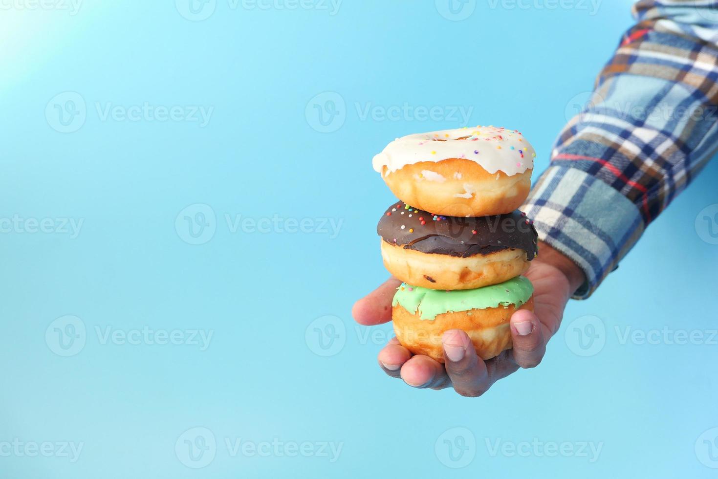 Close-up of hand holding donuts on blue background photo