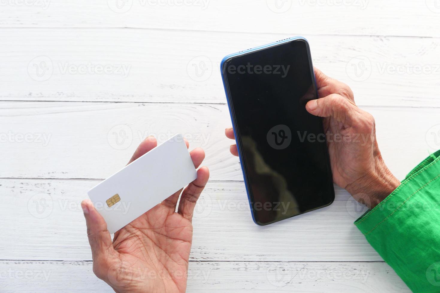 Senior woman holding a credit card and using a smartphone for shopping online photo