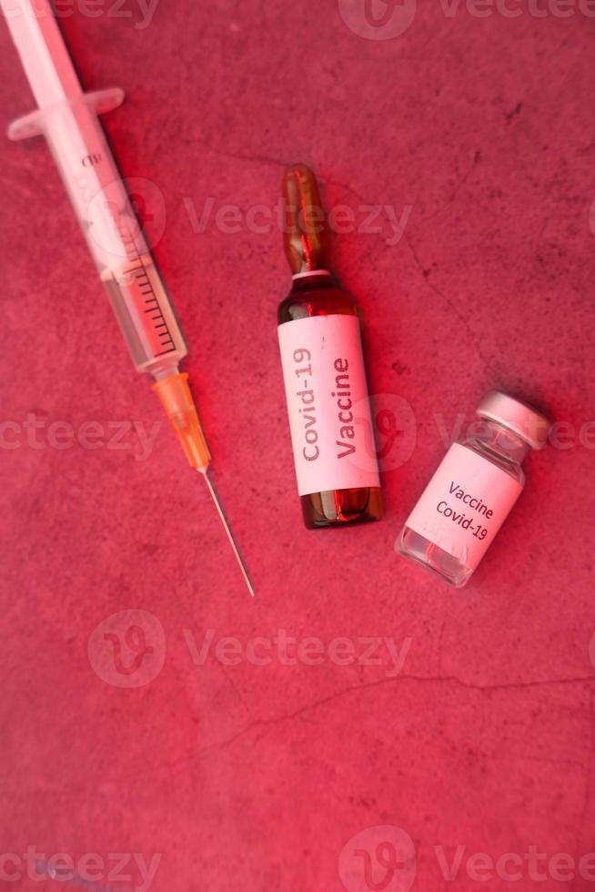 Primer plano de la vacuna contra el coronavirus y la jeringa sobre fondo rojo. foto