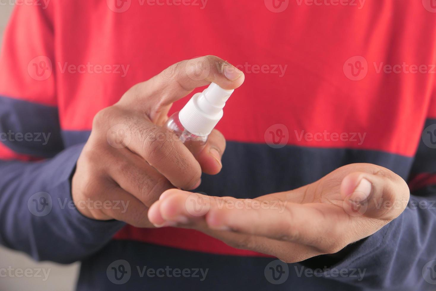 primer plano, de, un, joven, utilizar, manos, desinfectante, spray foto