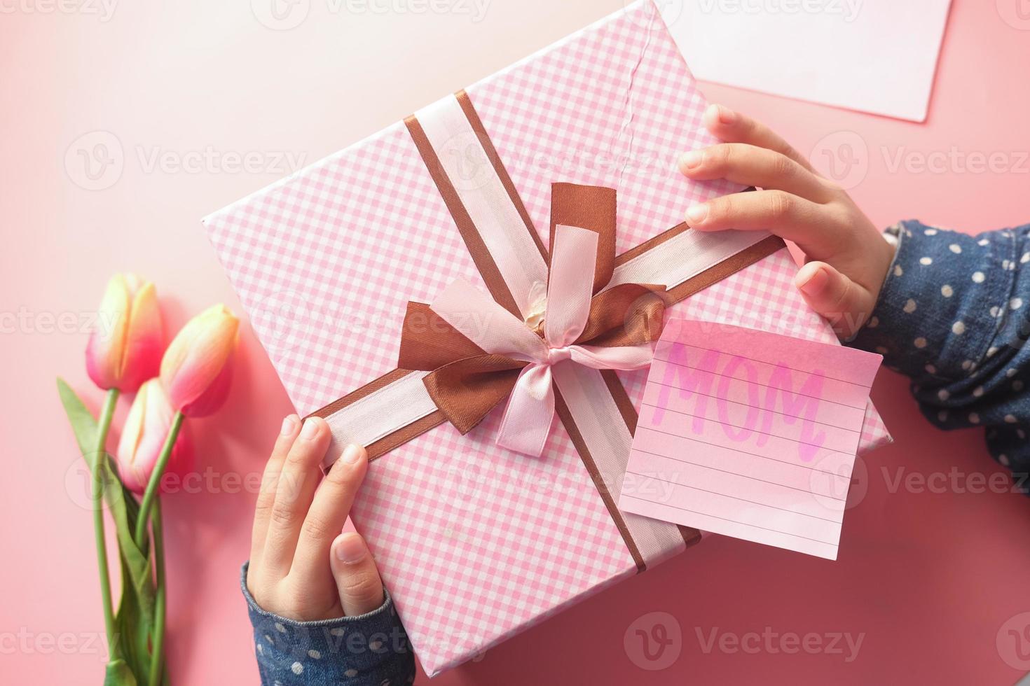 Mother's day concept of child hand holding pink color gift box photo