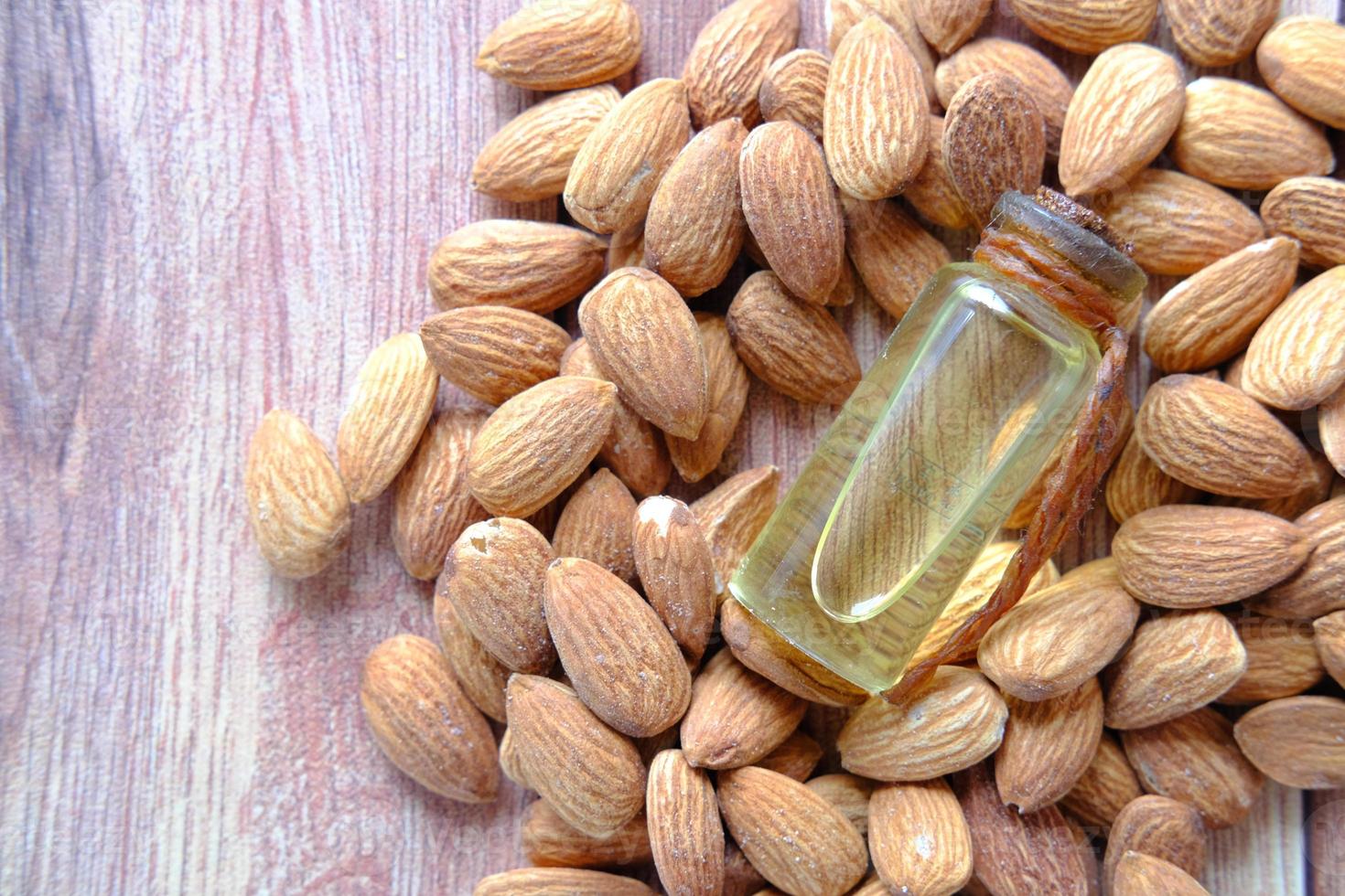 Aceite de almendras en botella sobre fondo de madera foto