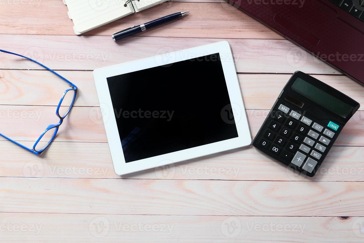 Flat composition of digital tablet and office stationery on wood background photo