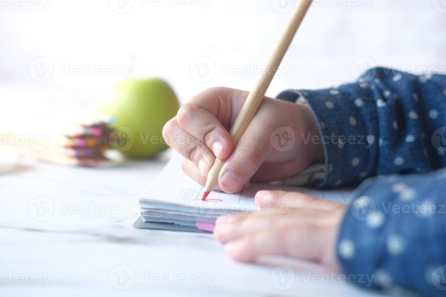 Close-up of a child hand drawing with colored pencil on a page photo