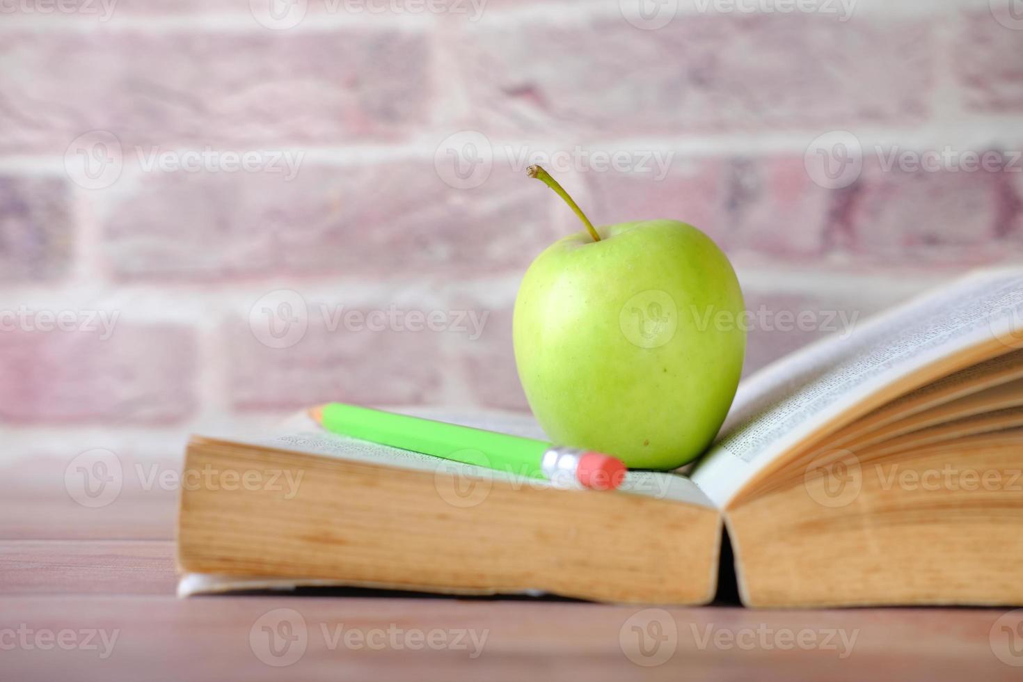 Green apple on a open book on table photo