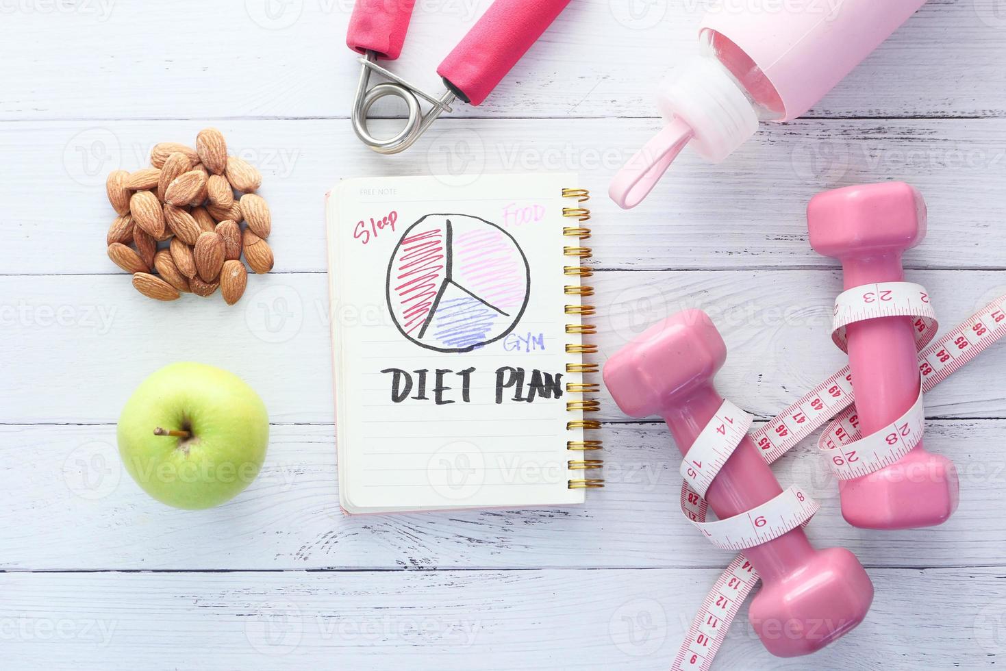 Diet plan with apple and dumbbell on white wooden background photo