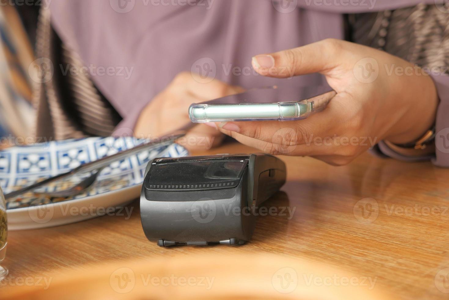 Mujer joven mediante pago sin contacto con smartphone foto