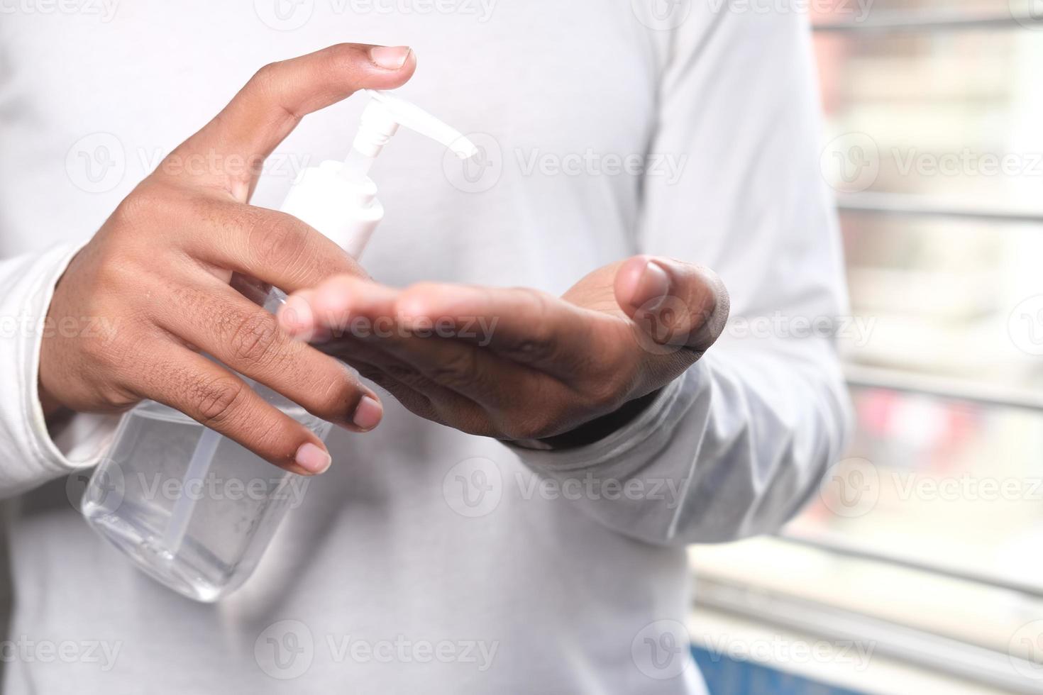Hombre usando líquido desinfectante para prevenir el virus corona foto