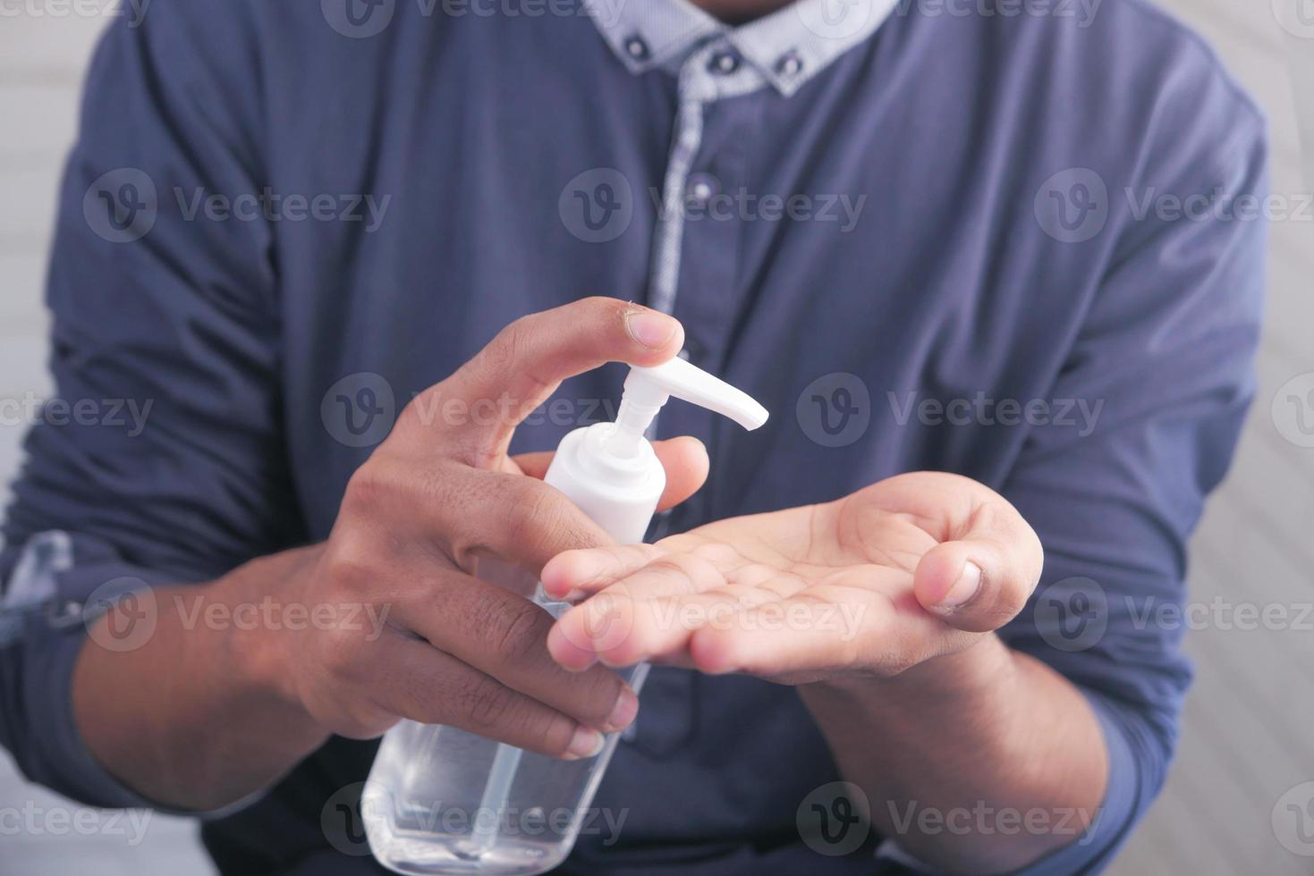 Hombre usando líquido desinfectante para prevenir el virus corona foto