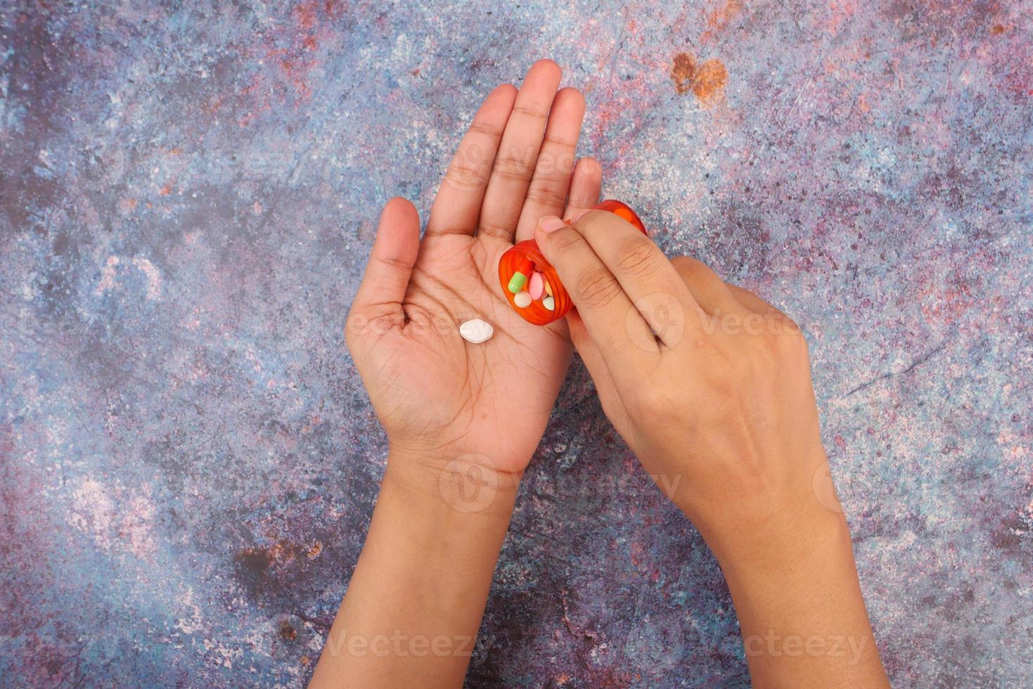 Vista superior de la mano de la mujer tomando pastillas en la mesa foto