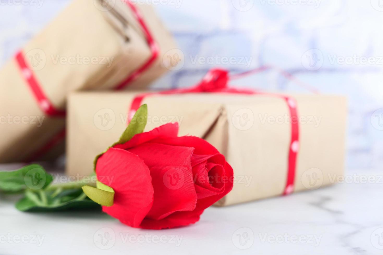 Close-up de rosa roja y pila de caja de regalo en la mesa foto