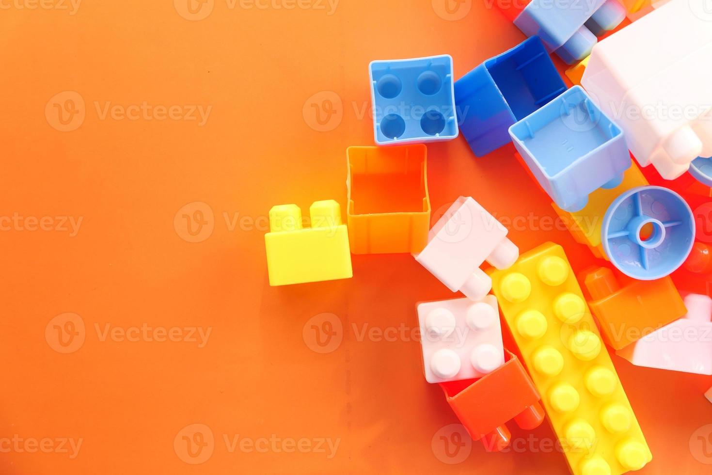 Colorful building blocks on orange table, close up photo