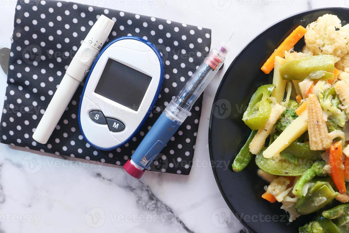 Herramientas de medición para diabéticos y bolígrafo de insulina y alimentos saludables en la mesa foto