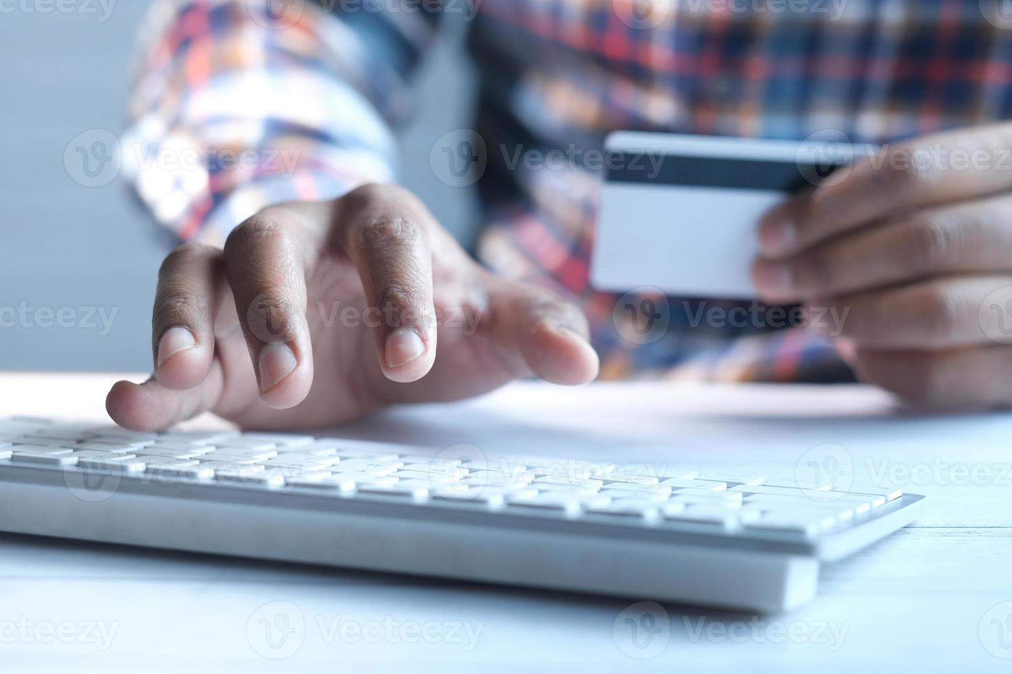 Man's hand holding a credit card and using laptop for shopping online photo