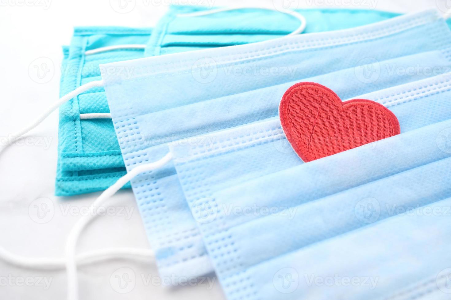 Surgical masks with heart shape and hand sanitizer on white background photo