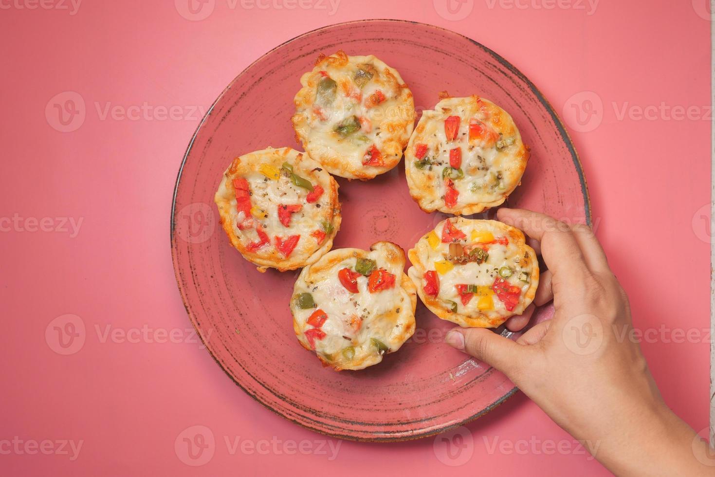 Top view of man's hand picking a slice of pizza from a plate photo