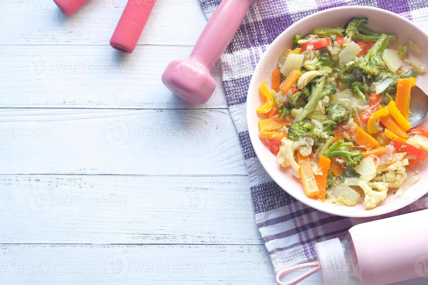 concepto de fitness con mancuernas, verduras frescas y cinta métrica en rosa foto