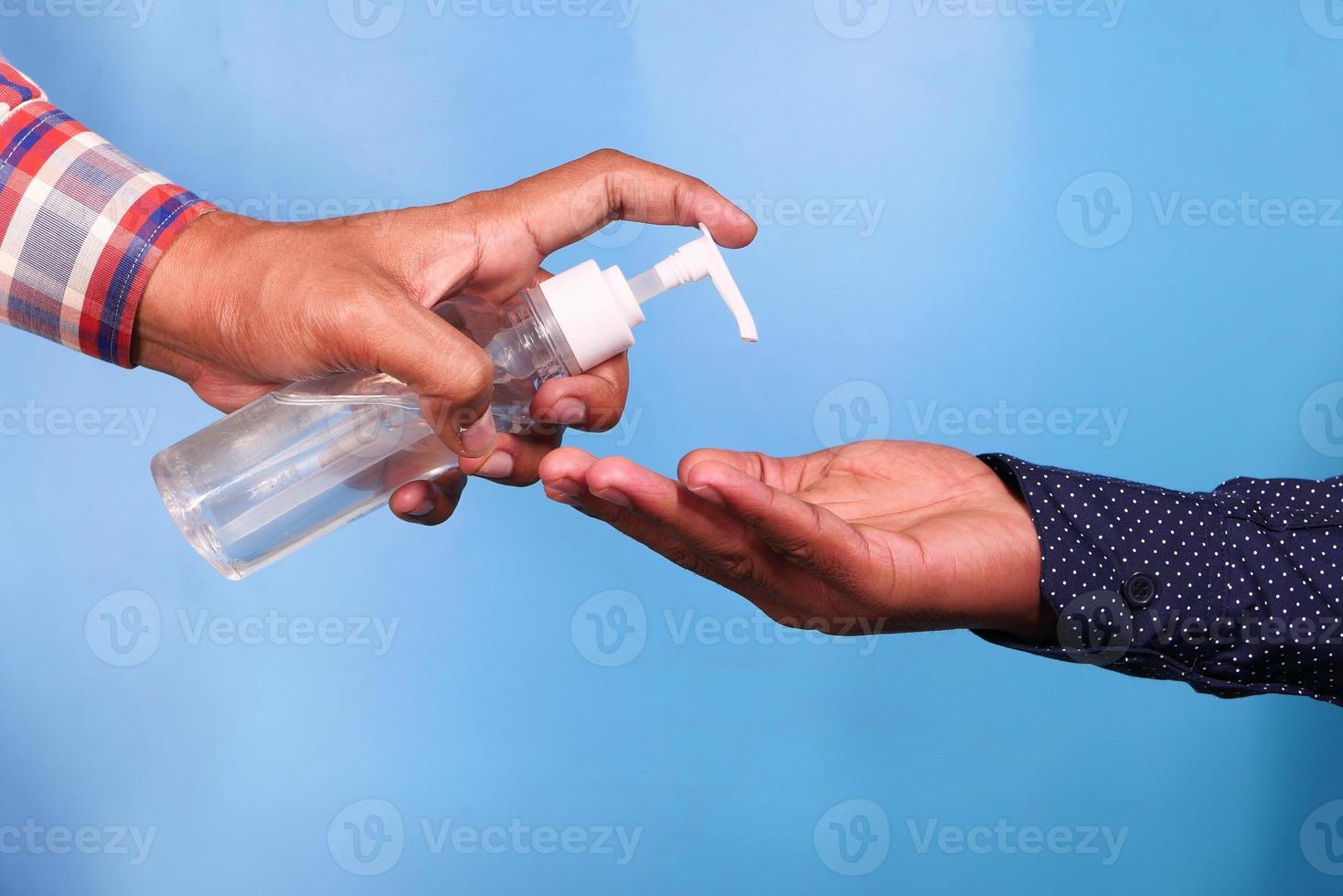 mano de una persona que le da líquido desinfectante a otra persona foto