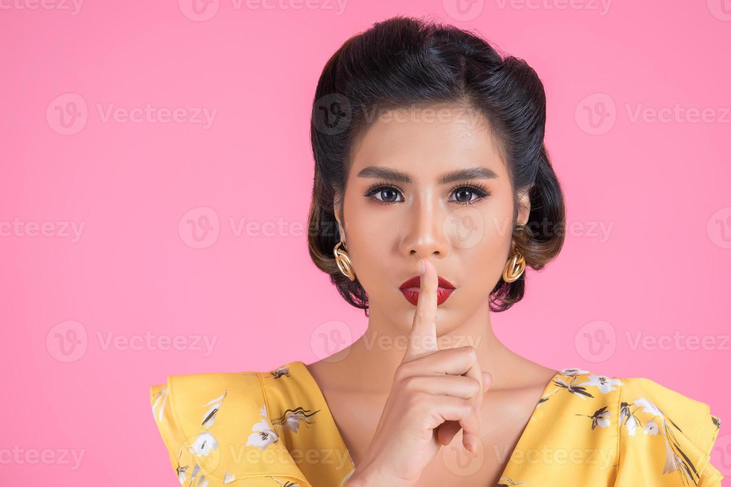 Asian woman with red lips and finger showing hush silence photo