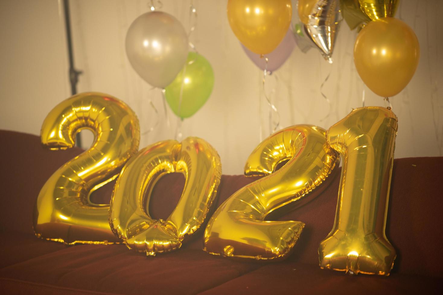 Gold 2021 balloons on red table with colorful balloons in background photo