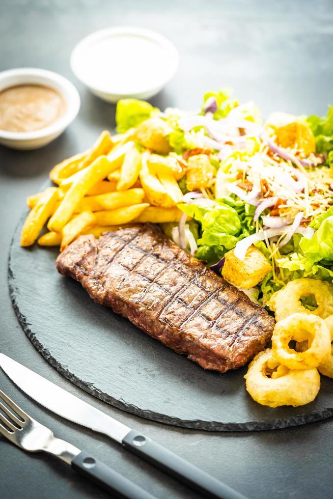 Filete de ternera a la parrilla con papas fritas y verduras frescas foto