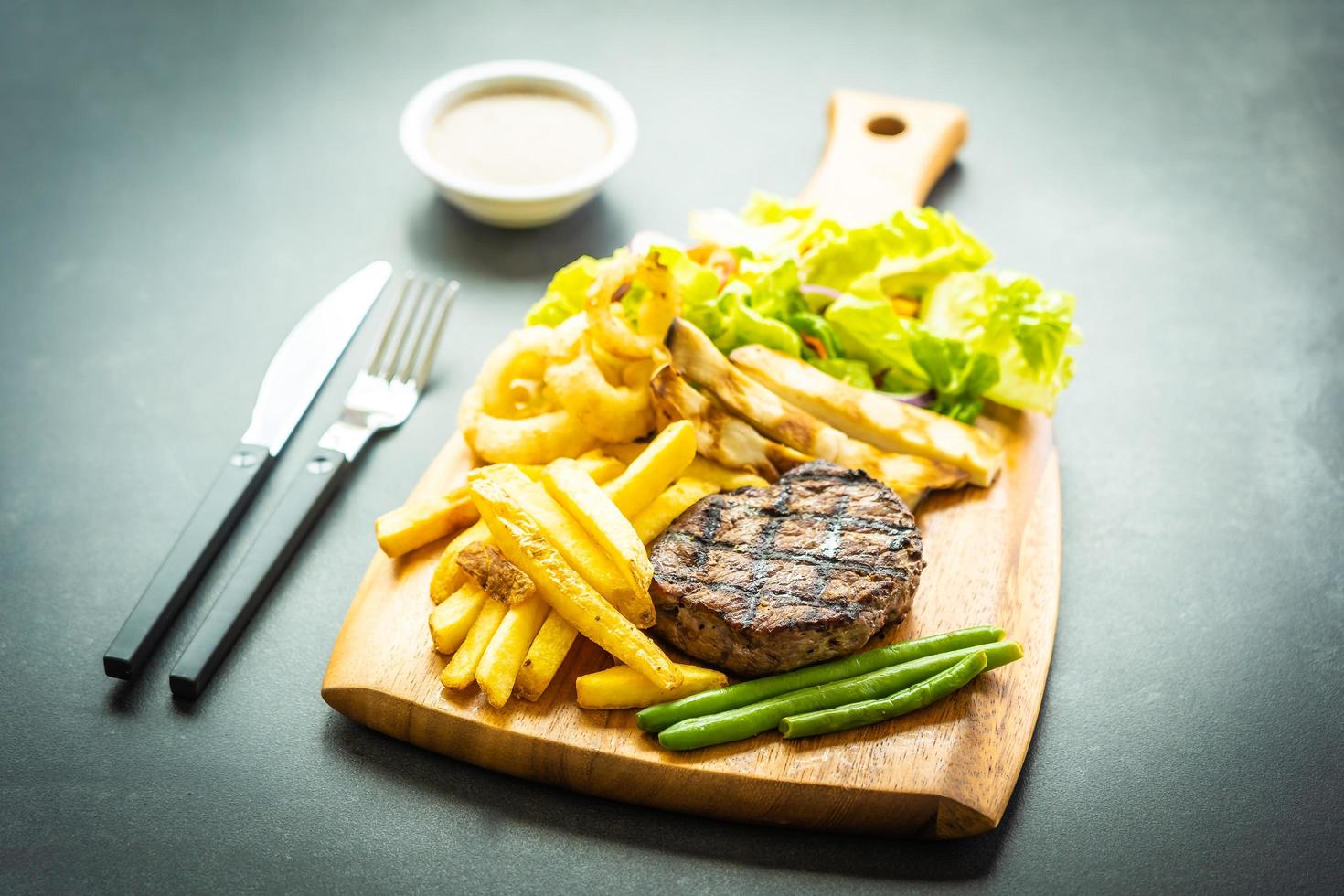 Grilled beef steak with french fries sauce and fresh vegetables photo