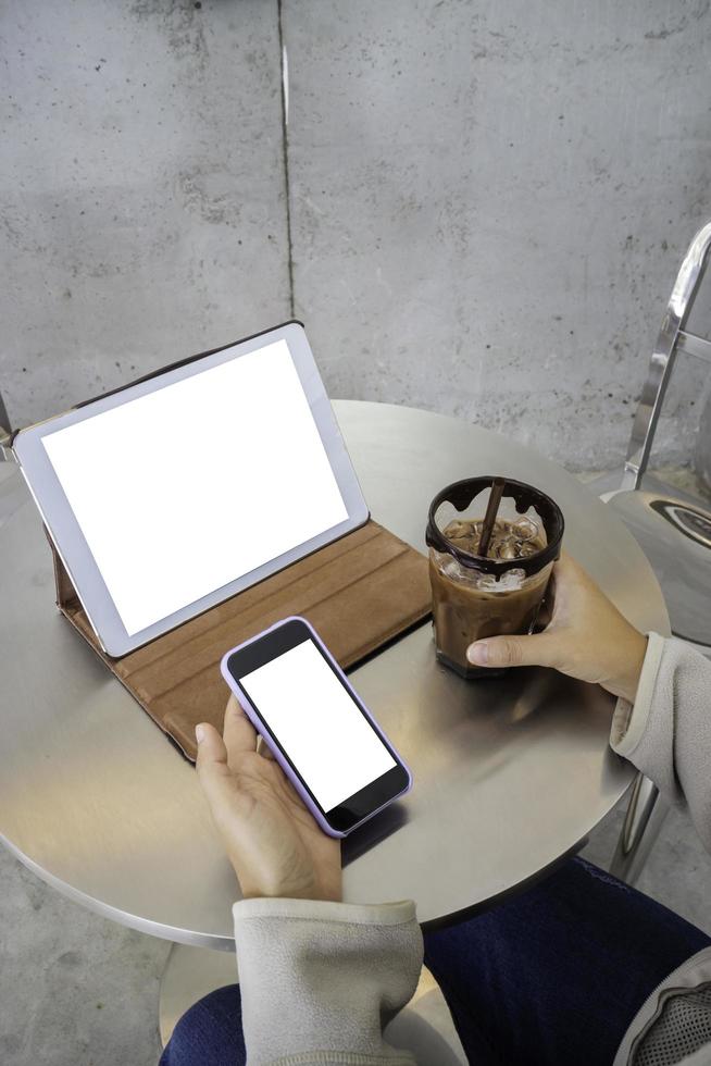 Person sitting at coffee shop with two blank mockup screens photo