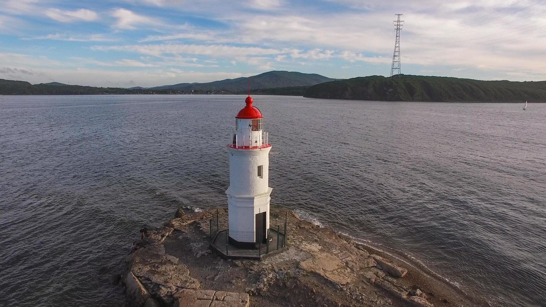 Seascape con un faro junto al cuerpo de agua con nublado cielo azul en Vladivostok, Rusia foto